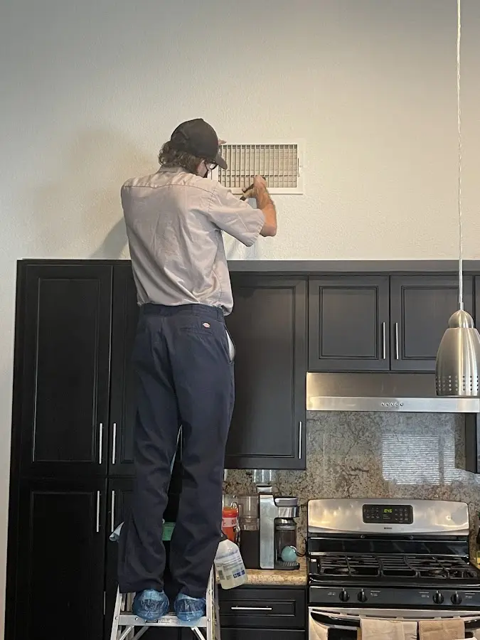 Technician inspecting an air vent during HVAC service in Mount Vista
